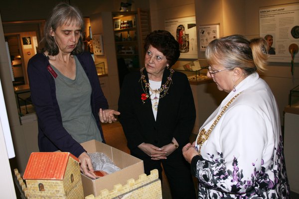 Three people looking at an artefact in a box. 